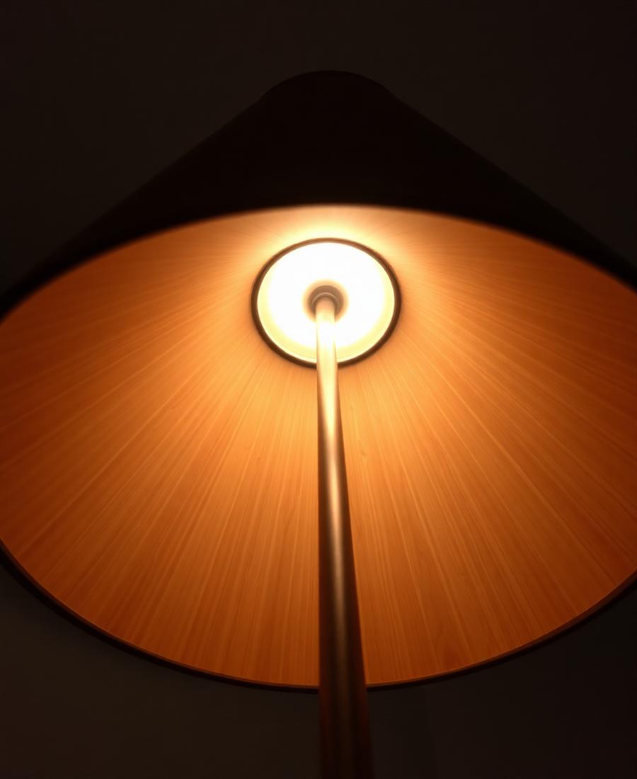 The wide plywood shade seen from below, lit warmly